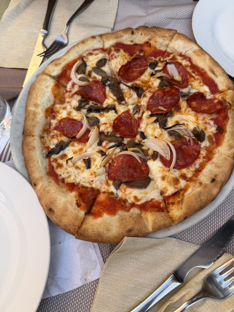 A pepperoni and mushroom pizza on a white plate at a Venice restaurant